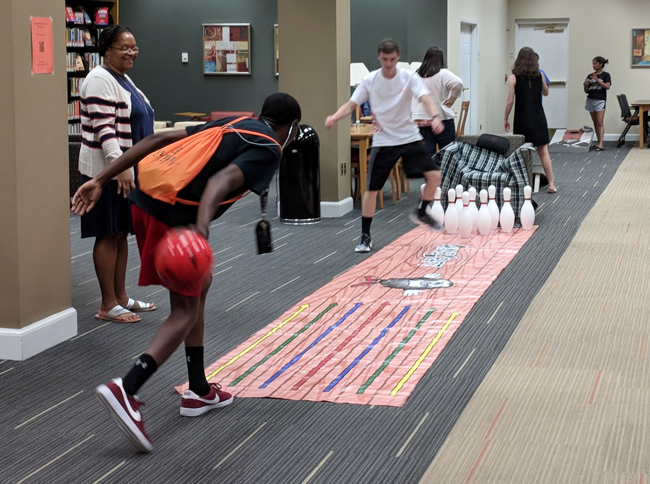 Students playing the different yard games; group of students in the front are bowling and the group of students in the back are playing corn hole