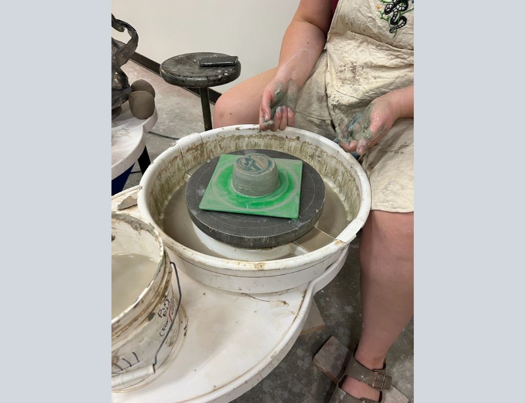 Shannon shapes her piece of clay into a beginning form to mold. She will work the clay as it spins on the pottery wheel, creating a piece of functional art.