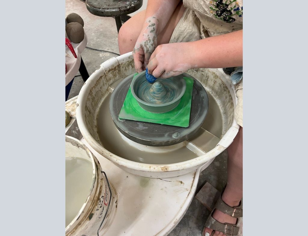 Using her hands and tools such as ribs and sponges, Shannon shapes a lemon juicer as it spins on the wheel, creating a final product which will be left to air dry and then fired in the kiln.